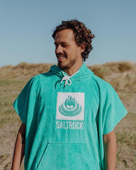 Man wearing Saltrock Corp changing towel robe in Turquoise with hood and front pocket outdoors