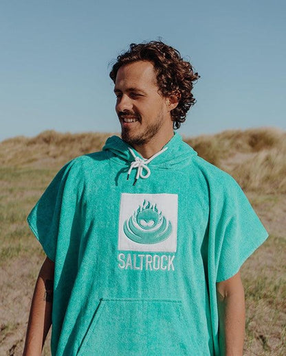 Man wearing Saltrock Corp changing towel robe in Turquoise with hood and front pocket outdoors