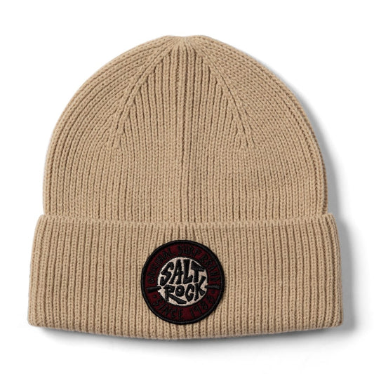 Front view of a Saltrock light brown knit ted beanie with a turn-up hem and round SR logo patch on a white background