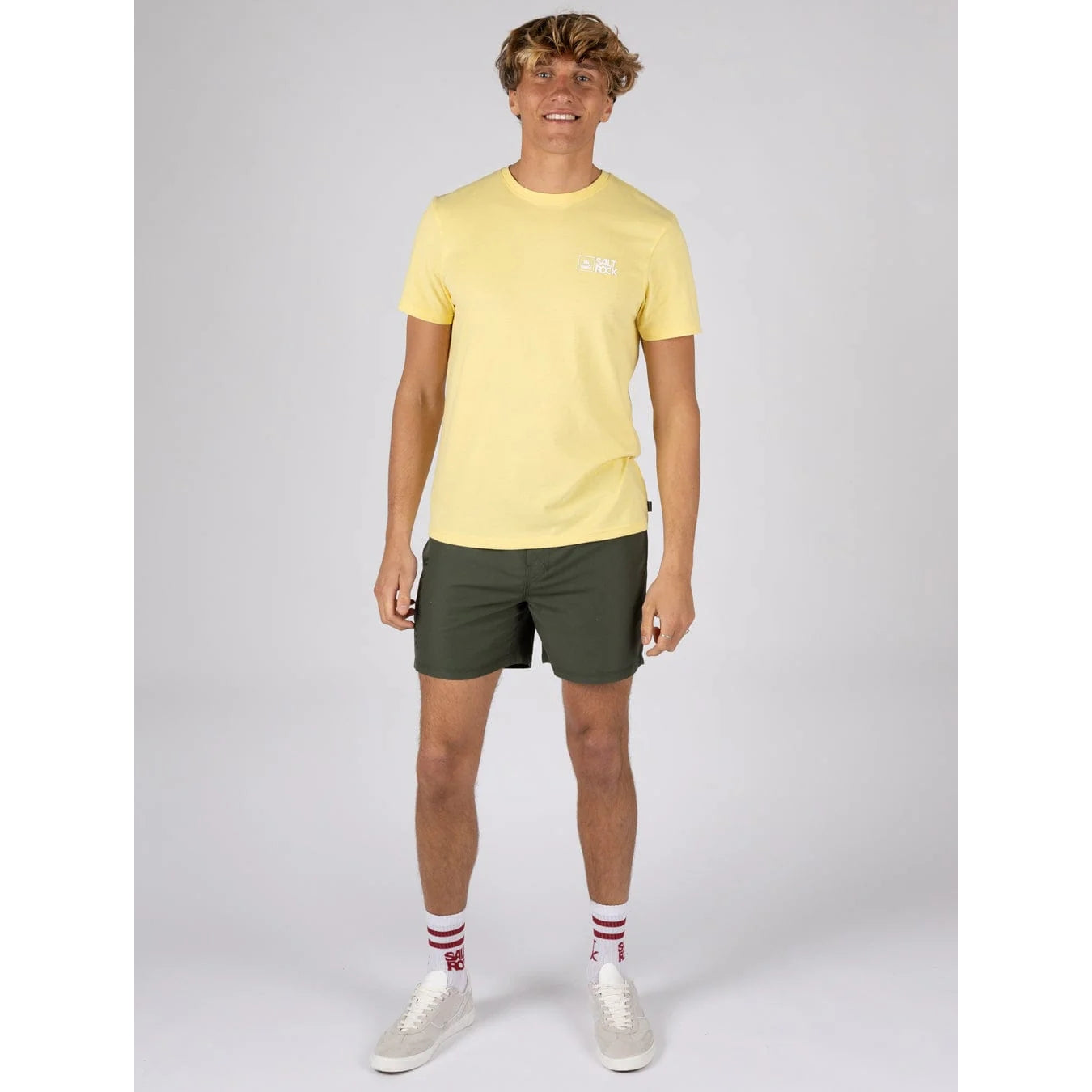 Man wearing a Saltrock short sleeve Essential t-shirt in light yellow with small chest logo with dark green shorts and white shoes