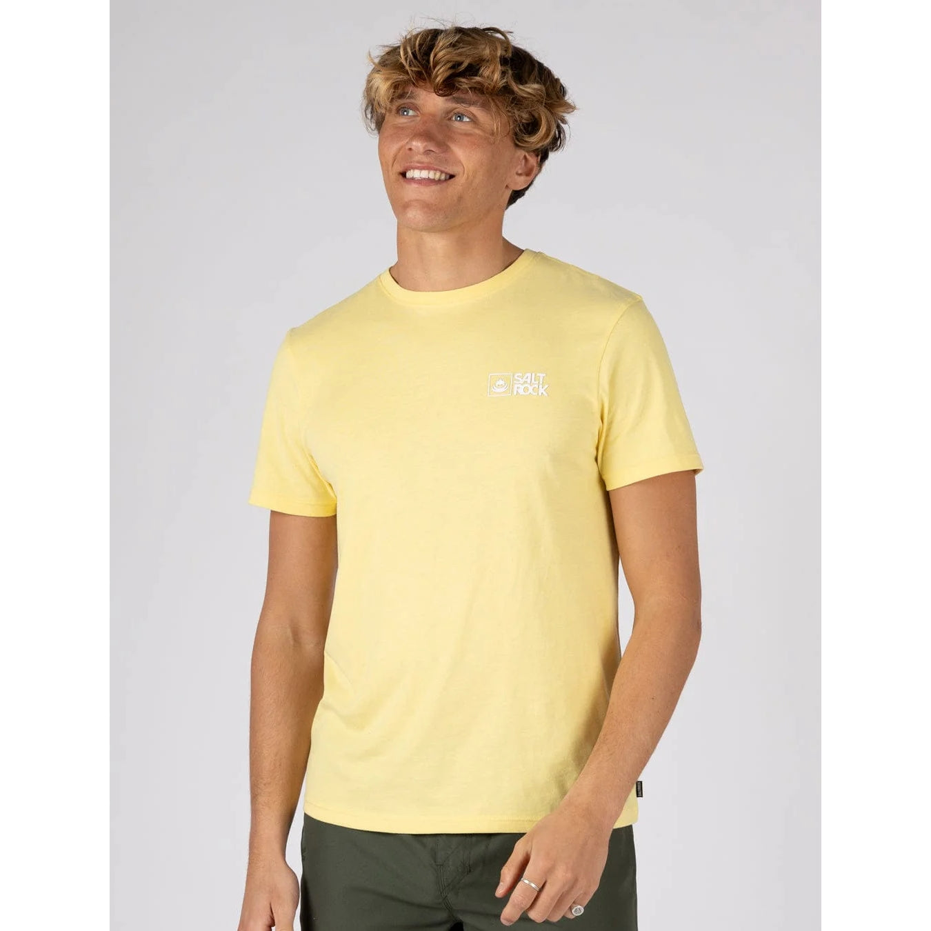 Front view of a man wearing a Saltrock short sleeve Essential t-shirt in light yellow with small chest logo with dark green shorts