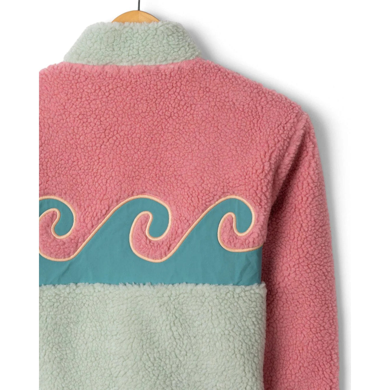 Close-up view of the back of a Saltrock kids Emery Wave fleece with wave applique on the back, in pink, turquoise and teal