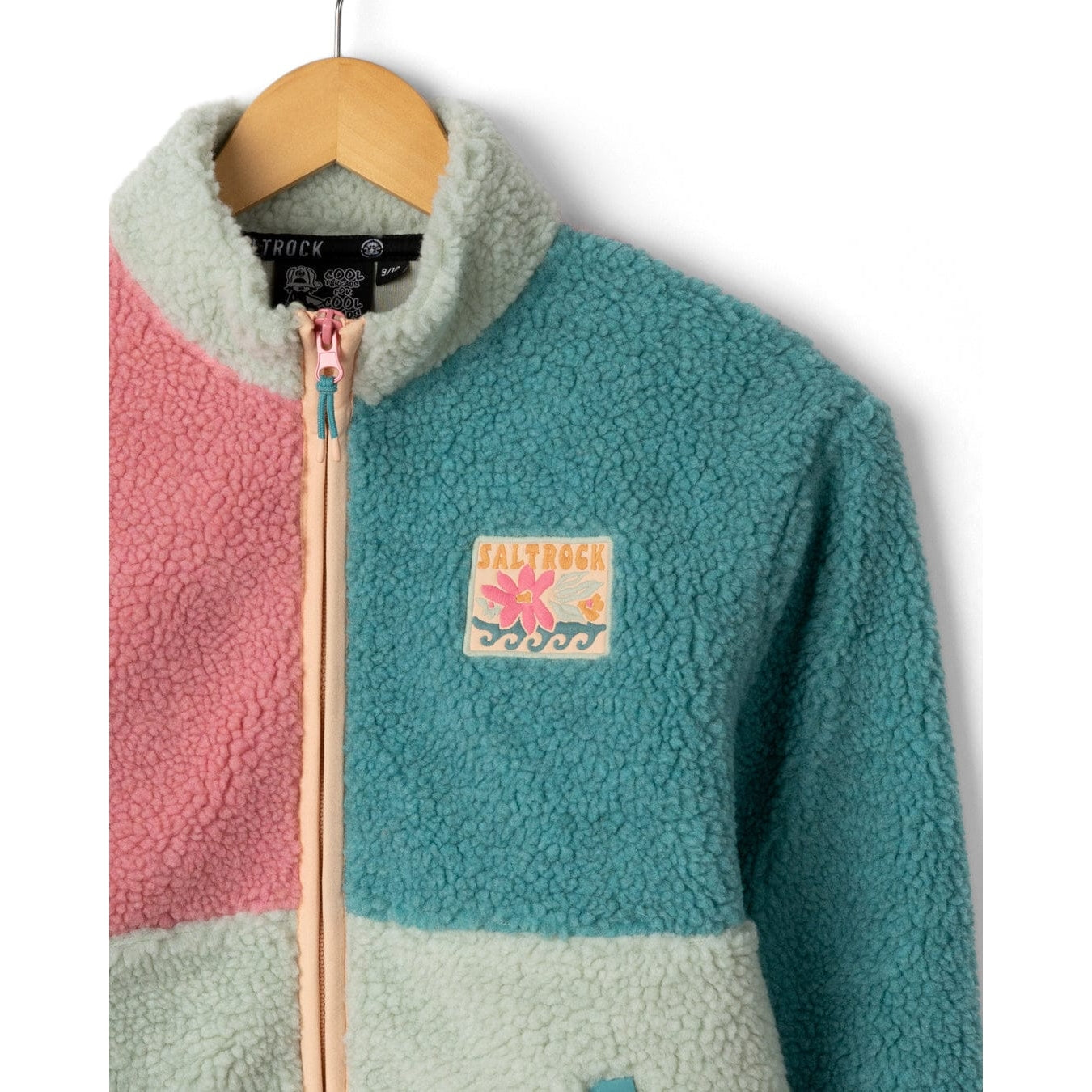 Close-up view of the front of a kids Saltrock Emery Wave full zip fleece in pink, teal and turquoise with logo