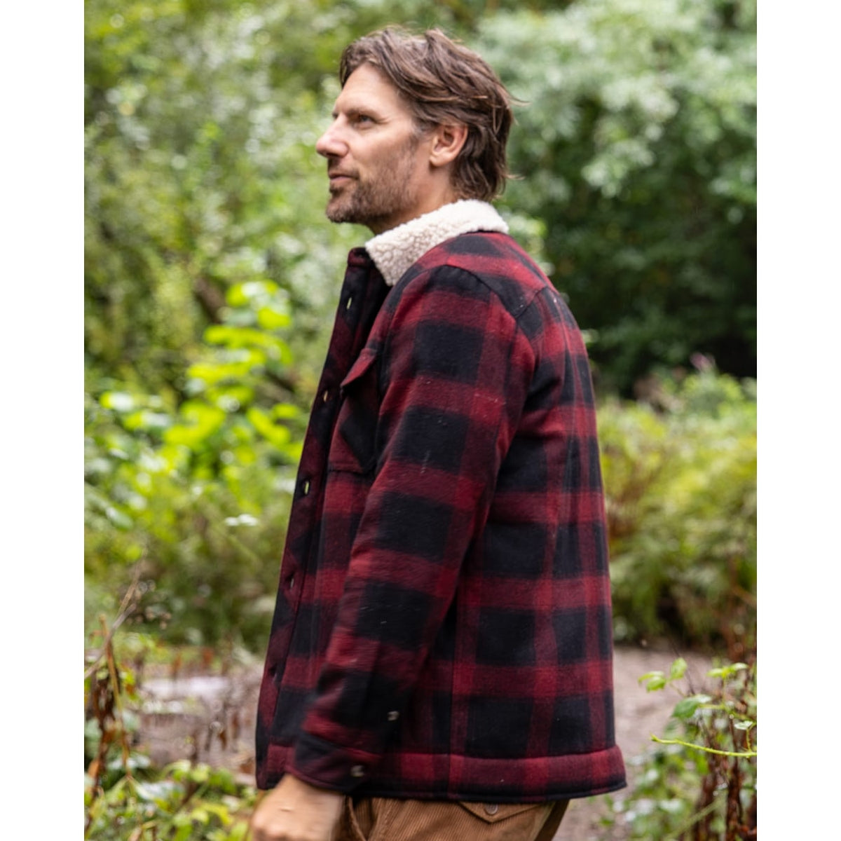 Side view of a man wearing a Saltrock Fisher Borg lined shacket with a dark red and black check pattern outer fabric and a cream collar lining.