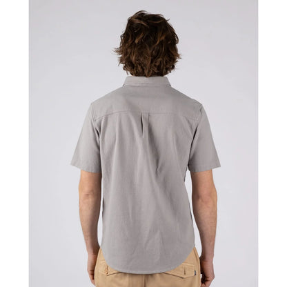 Back view of a man wearing a Saltrock short sleeve Polperro button shirt in grey with a waffle texture with tan trousers.