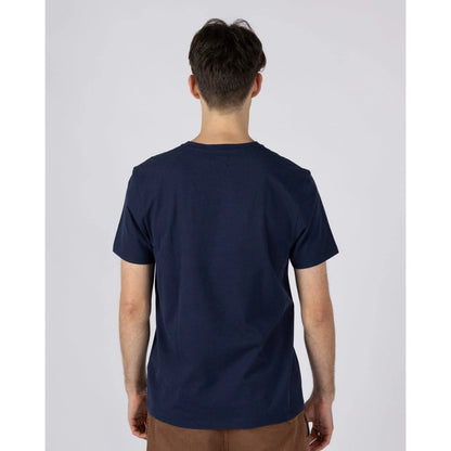 Back view of a man wearing a Saltrock short sleeve Tribal Stripe t-shirt in navy, with a multicoloured stripe print across the chest.