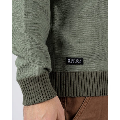 Close-up view of a Saltrock knitted Callum jumper in green with ribbed cuffs, bottom hem and small black logo label