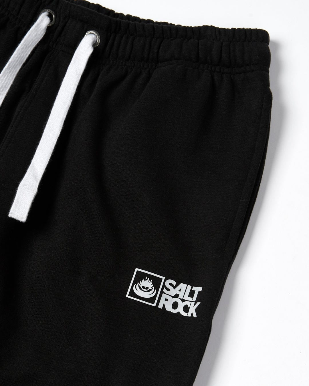 Close up view of a pair of mens Saltrock black jogger sweat trousers with printed logo on a white background