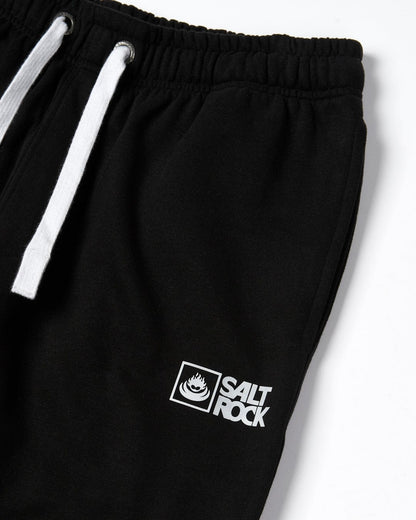 Close up view of a pair of mens Saltrock black jogger sweat trousers with printed logo on a white background