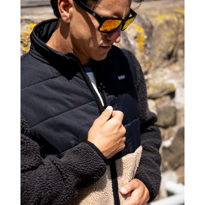 Close-up of a man wearing a Saltrock black and beige Rafe zip sherpa fleece outdoors