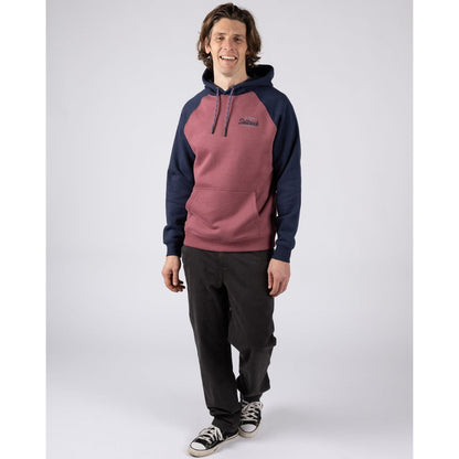 Man wearing a Saltrock Postcard Script raglan pop hoodie in dark pink with navy blue sleeves and hood