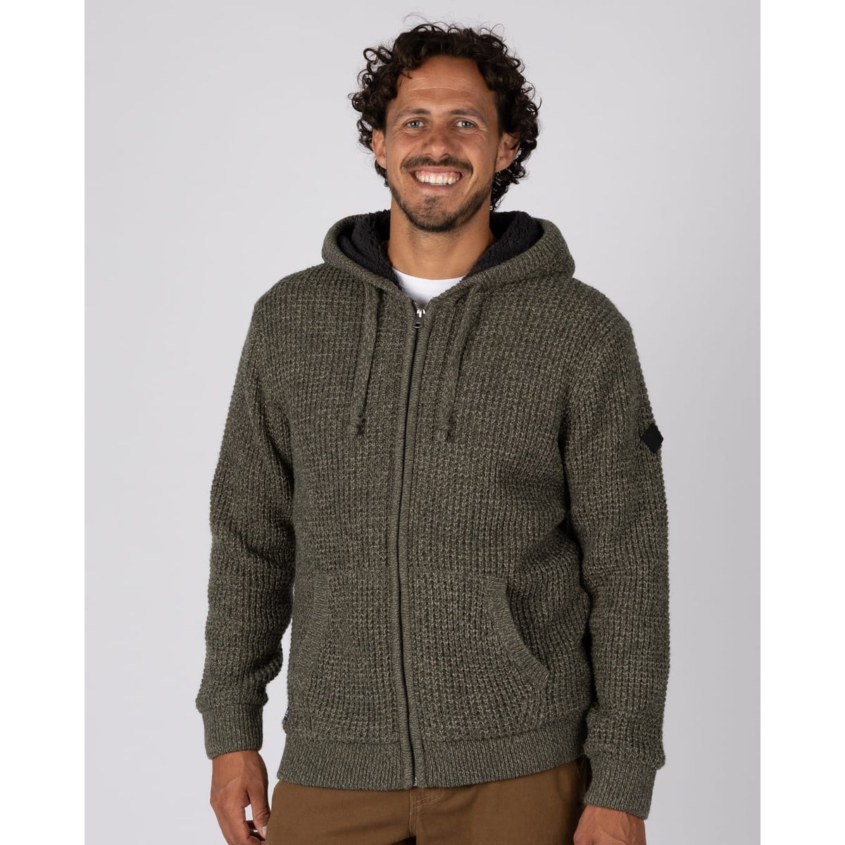 Front view of a man wearing a Saltrock dark green Markus knitted hoodie with a fluffy navy Borg lining with brown trousers.