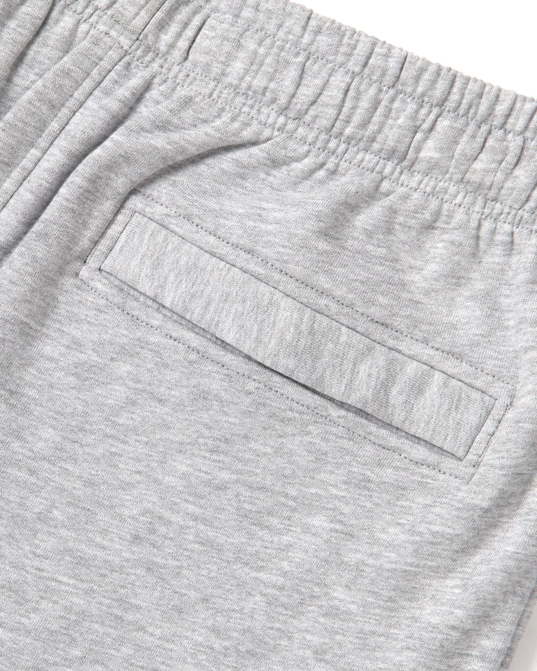 Close up of the elastic waist and back pocket of a pair of mens Saltrock grey jogger sweat trousers on a white background