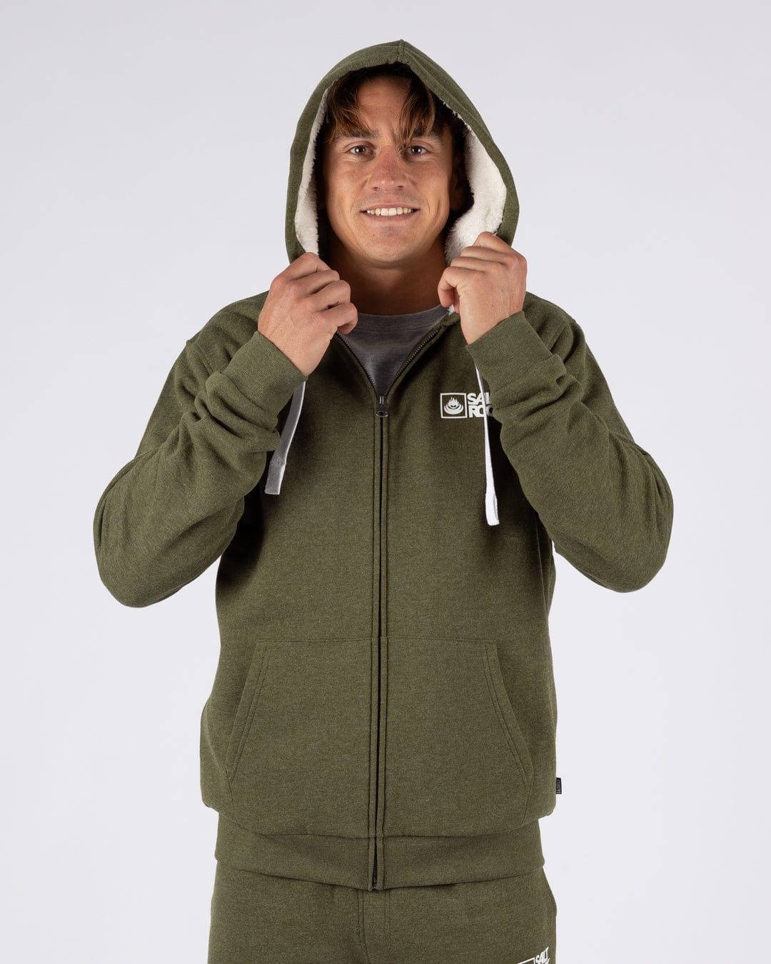 A man wearing a Saltrock Essential full zip faux fur lined hoodie in khaki green with the hood up.