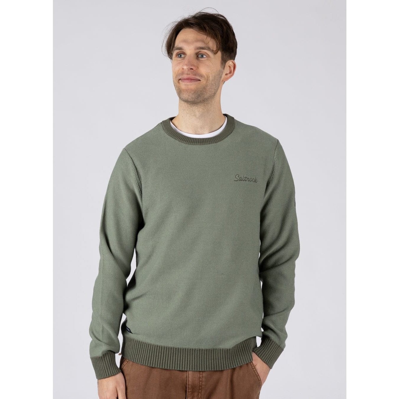 Front view of a man wearing a green Saltrock knitted Callum jumper with round neckline, ribbed cuffs, bottom, hem and neckline trim with small embroidered logo on the chest