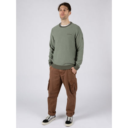 Man wearing a green Saltrock knitted Callum jumper and brown cargo pants on a white background