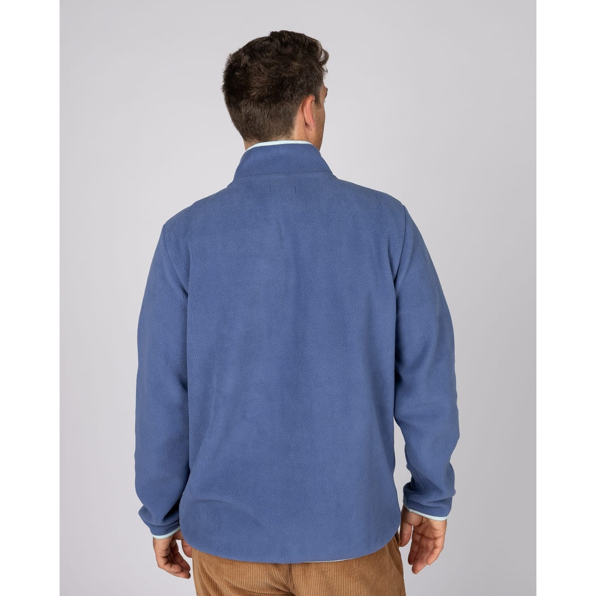 Back view of a man wearing a Saltrock Leo full zip fleece in blue with turquoise trim.