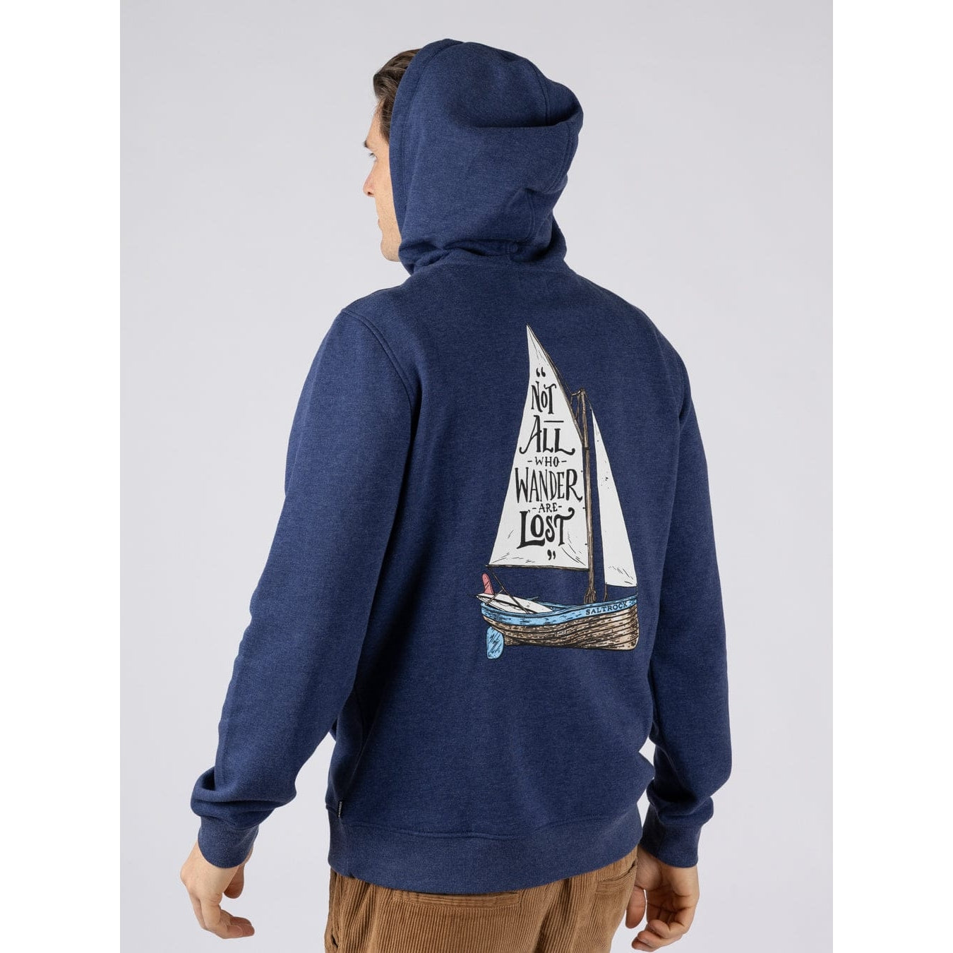 A man wearing a Saltrock Lost Ships pop hoodie in blue featuring a print of the quote "Not all who Wander are Lost"