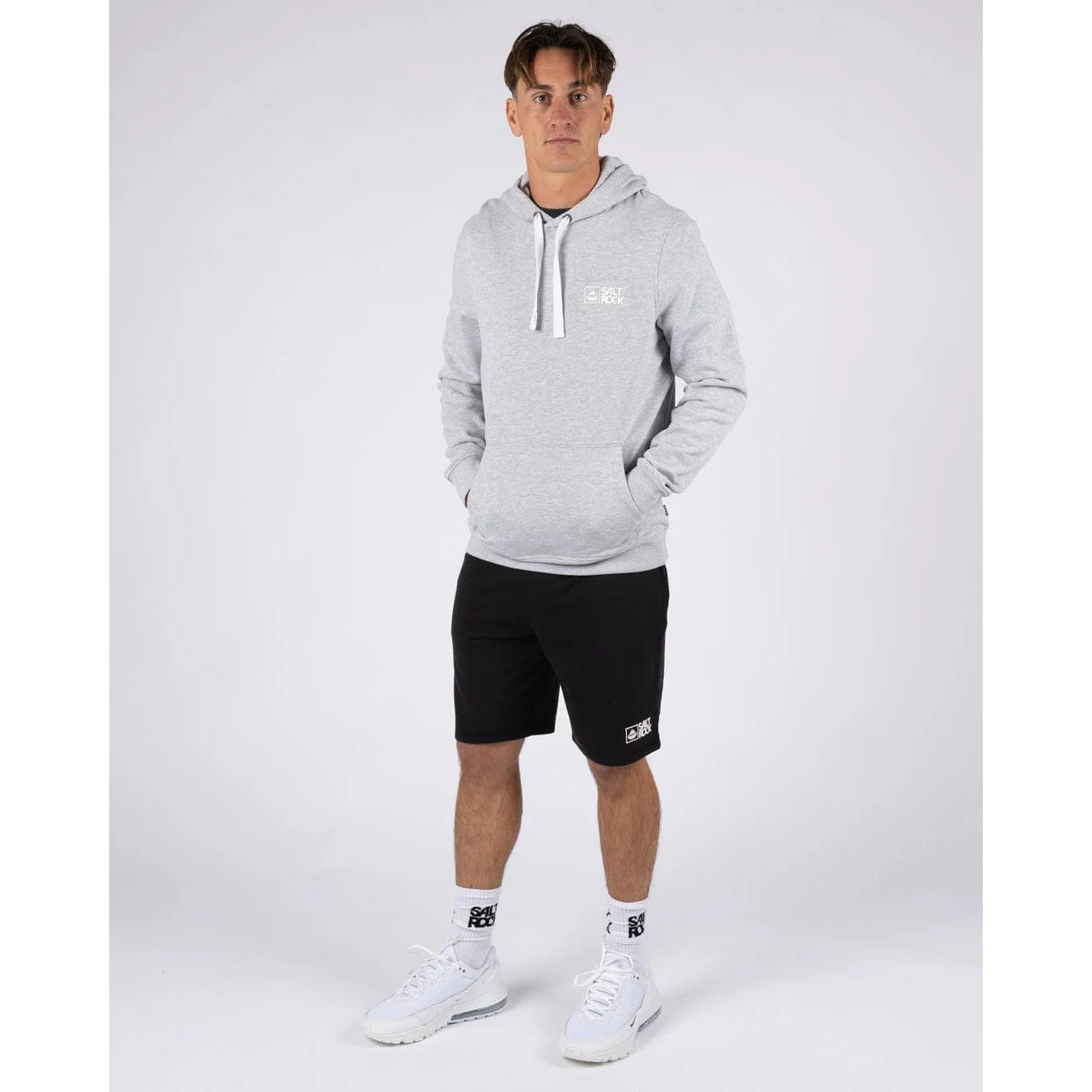 Man wearing a grey Saltrock Original pop hoodie and black shorts on a white background