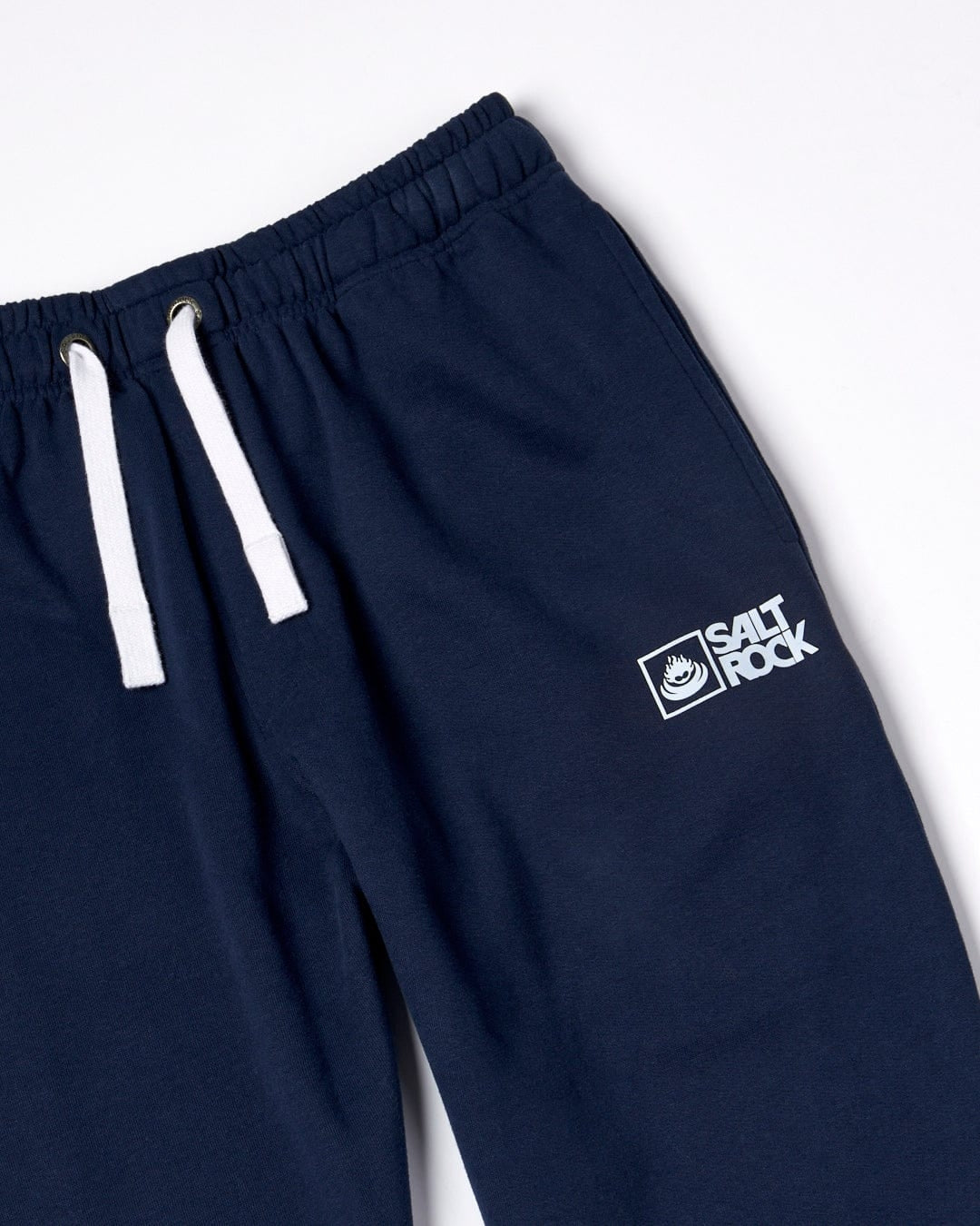 Close up of a pair of Saltrock mens Original jogger sweat trousers in dark blue with white waist drawstring and printed Saltrock logo on a white background
