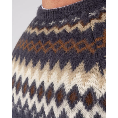 Close-up view of the geometric Fairisle style pattern on the chest of a mens Saltrock Fairisle Rock crew neck knitted jumper in blue.