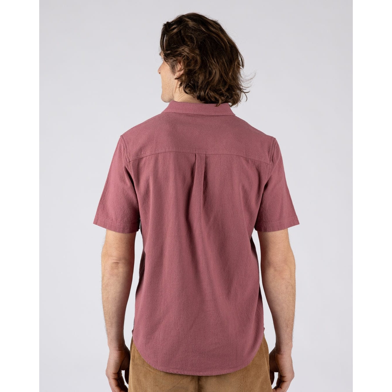 Back view of a man wearing a short sleeve Saltrock button through Polperro shirt in dark pink.