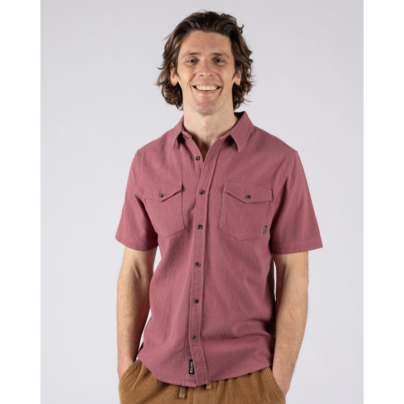 Front view of a man wearing a short sleeve Saltrock button through Polperro shirt in dark pink.