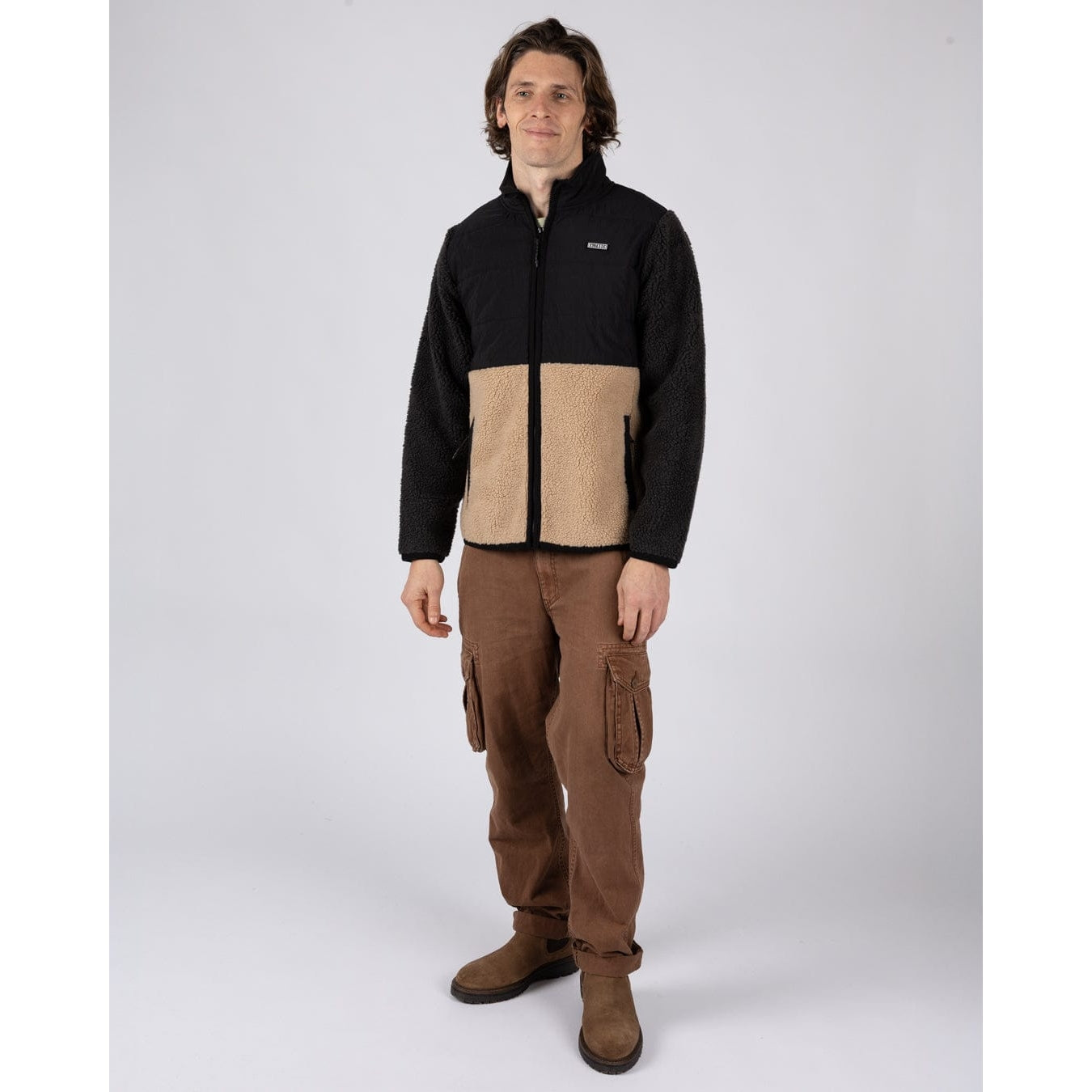 Man wearing a black and beige Saltrock Rafe zip fleece jacket with brown trousers