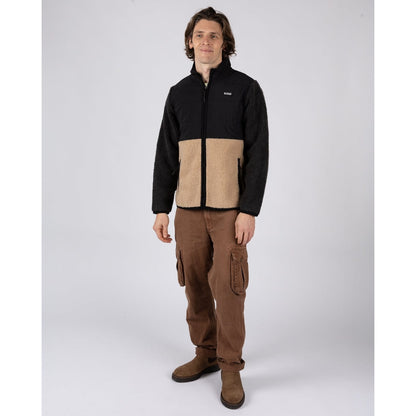 Man wearing a black and beige Saltrock Rafe zip fleece jacket with brown trousers