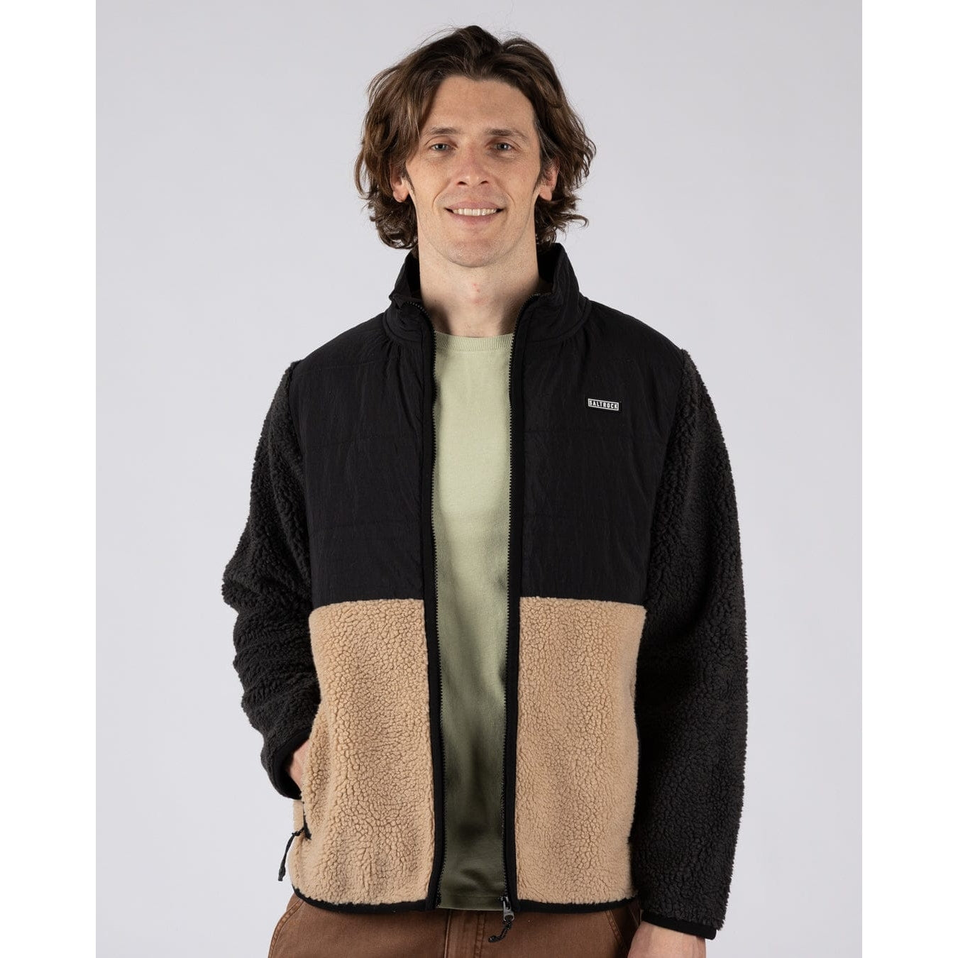 Front view of a man wearing a Saltrock Rafe colour block zip fleece in black and beige with the front unzipped.