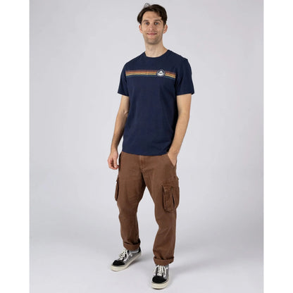 Man wearing a Saltrock short sleeve Tribal Stripe t-shirt in navy, with a multicoloured stripe print across the chest with brown trousers and trainers.