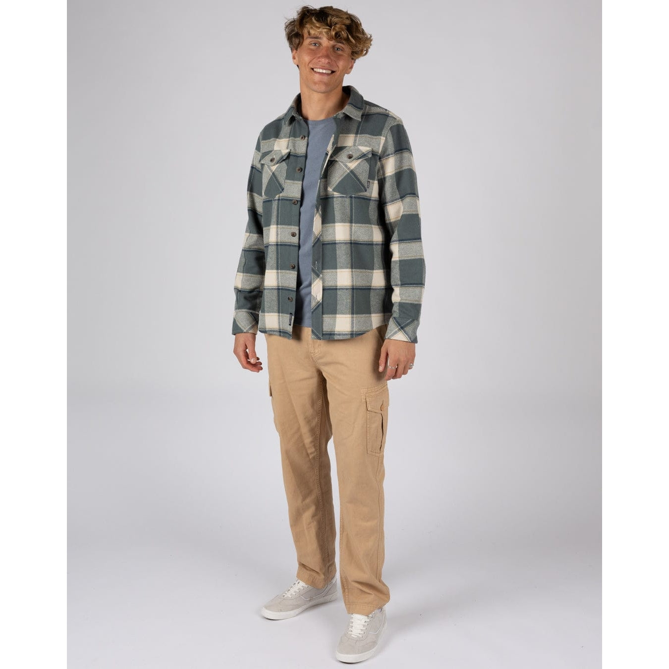 Man wearing a Saltrock Strait long sleeve check shirt in dark teal green with chest pockets and tan trousers