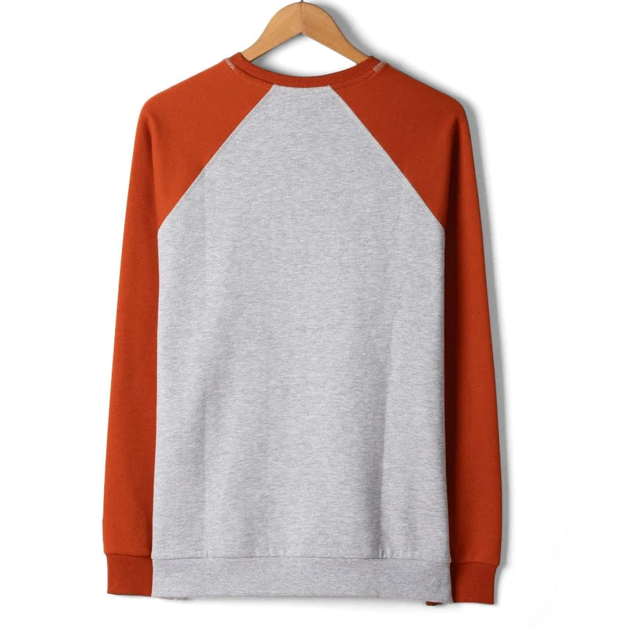 Long-sleeve shirt with grey body and orange sleeves on a hanger against a white background