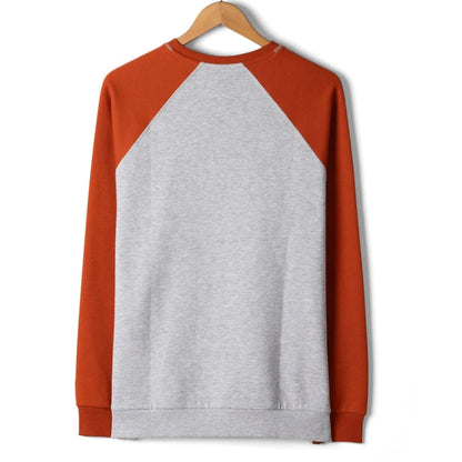 Long-sleeve shirt with grey body and orange sleeves on a hanger against a white background