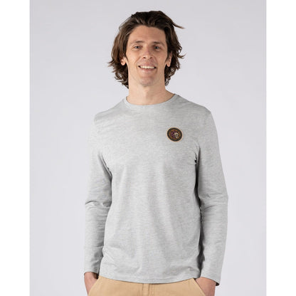 Front view of a man wearing a Saltrock Trail Badge long sleeve t-shirt in grey with a circular surf and skull themed print