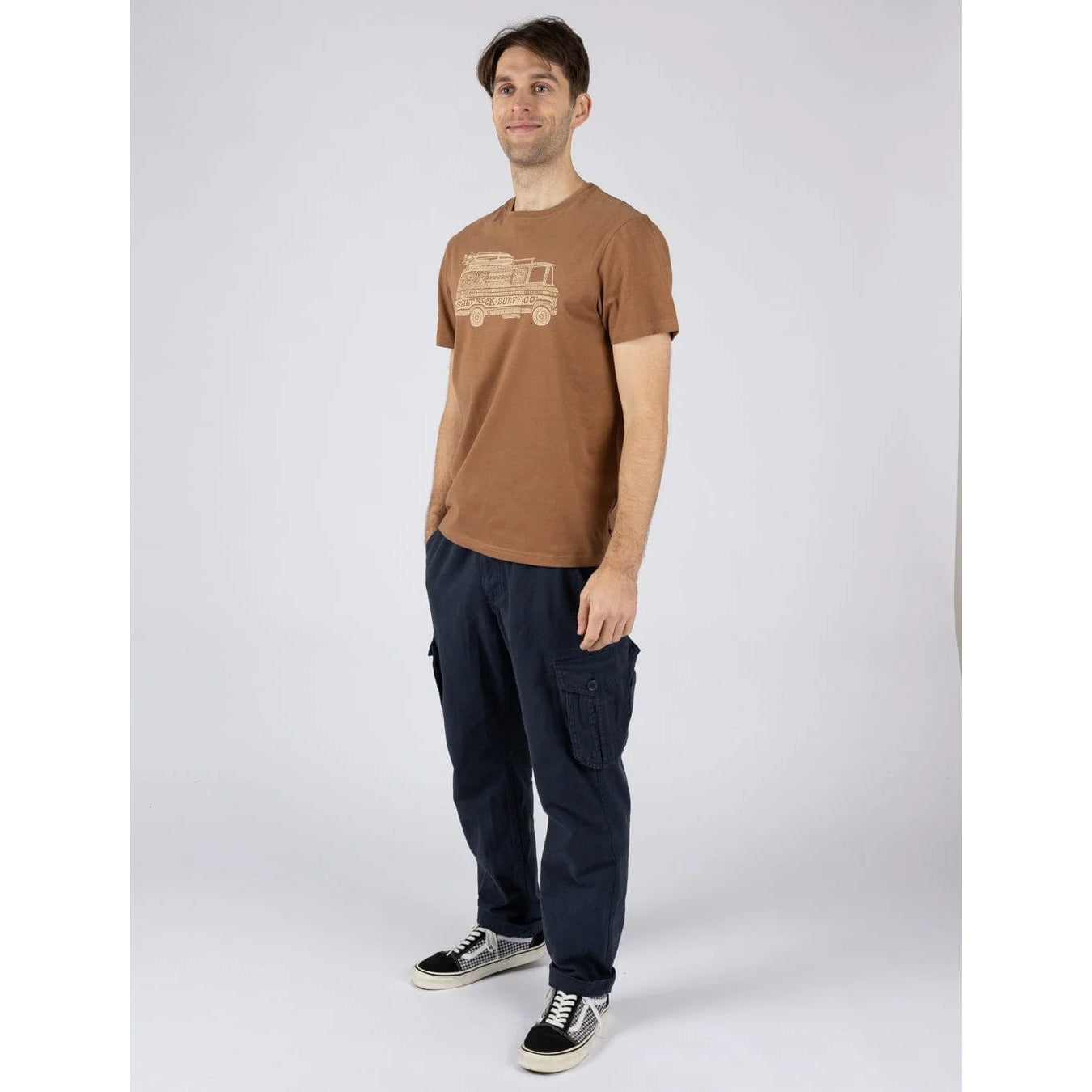 Man wearing a Saltrock short sleeve Trail Bus print t-shirt in brown with navy trousers