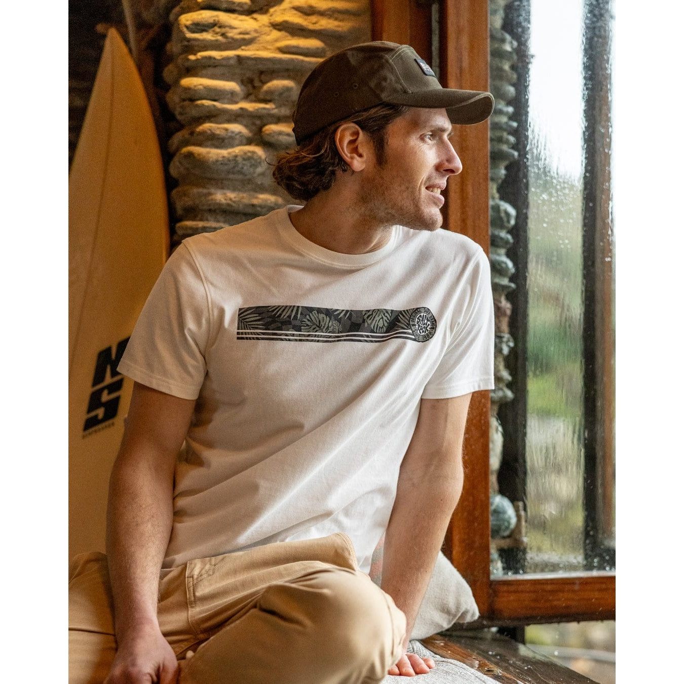 Front view of a man wearing a Saltrock short sleeve Warp Surf Stripe t-shirt in cream with print across the chest