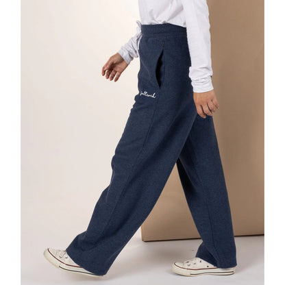 Woman wearing Saltrock blue marl sweat trousers with white logo and white sneakers on a plain background