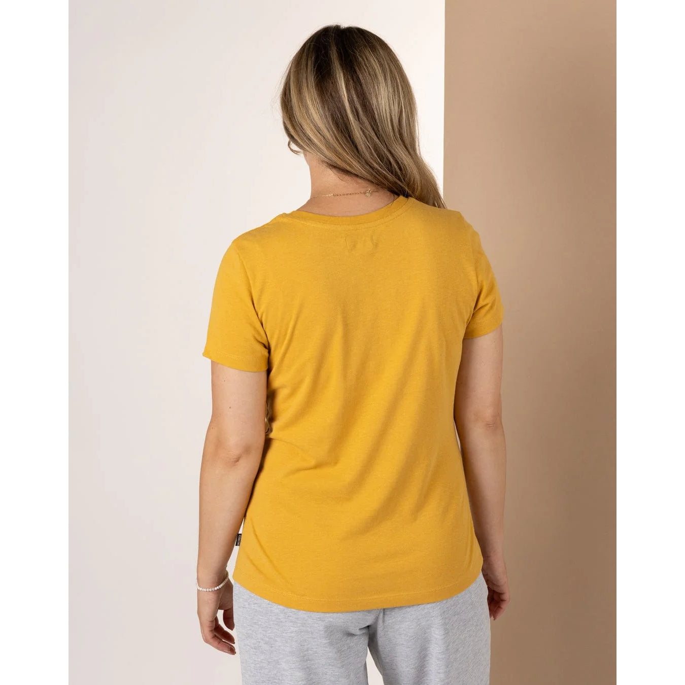 Back view of model wearing Saltrock womens Velator t-shirt in gold yellow short sleeve crew neck casual fit