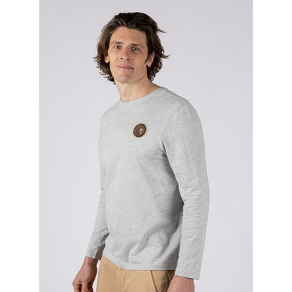 Side view of a man wearing a Saltrock Trail Badge long sleeve t-shirt in grey with a circular surf and skull themed print