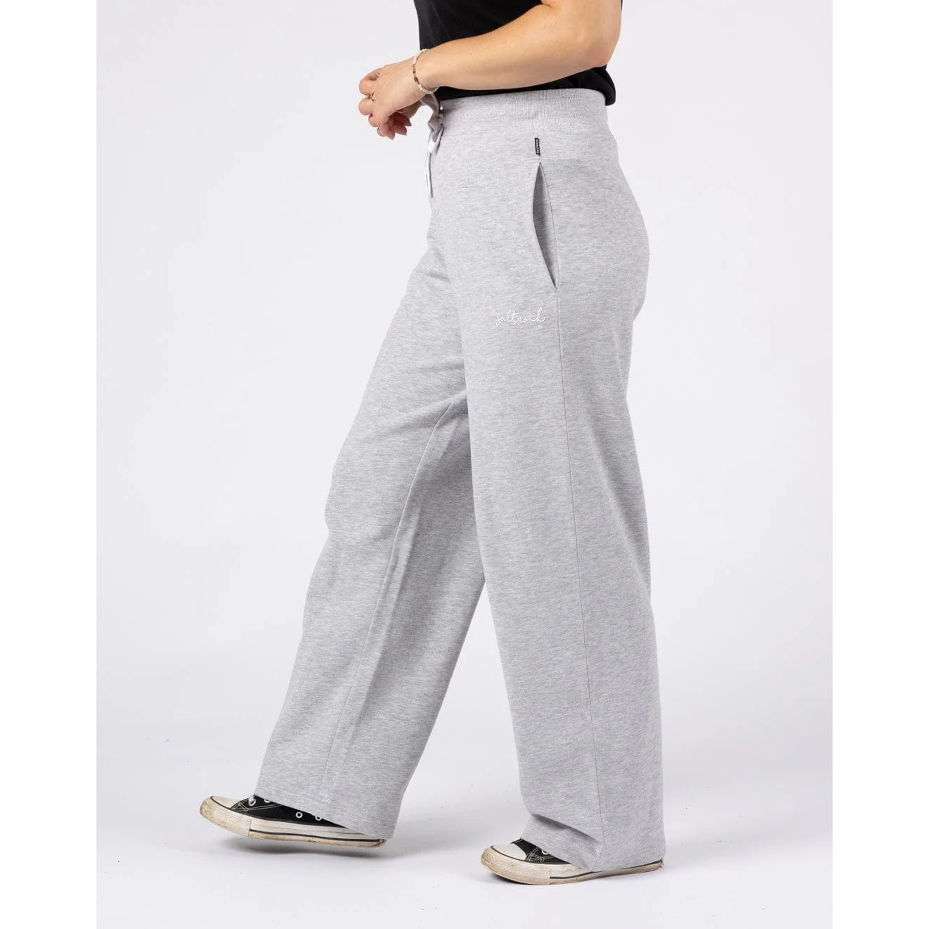 Side view of a woman wearing a pair of Saltrock sweat trousers in grey with hip pockets.