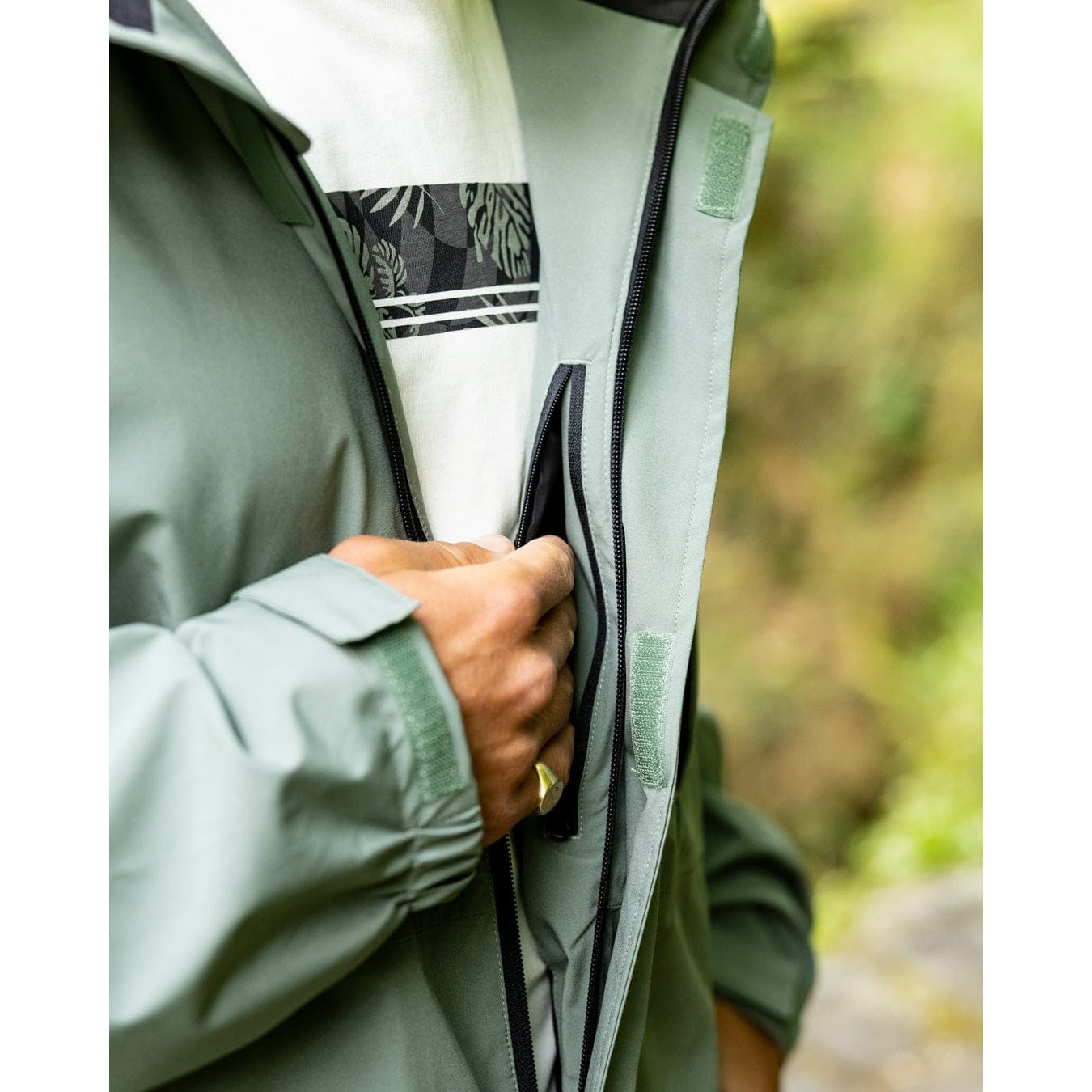 Close-up view of an internal zip pocket of a Saltrock Whistler II waterproof hooded jacket in light green outdoors