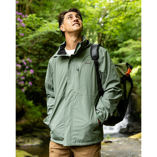 Front view of a man wearing a Saltrock Whistler II waterproof hooded jacket in light green outdoors.