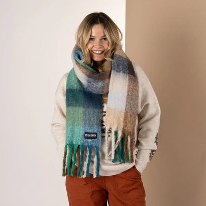 Woman wearing a Saltrock Harvest check pattern scarf in blue, green and brown tones on a beige background