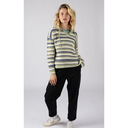 Woman wearing a striped Saltrock Aurelia knitted hoodie in green, blue and white with black pants