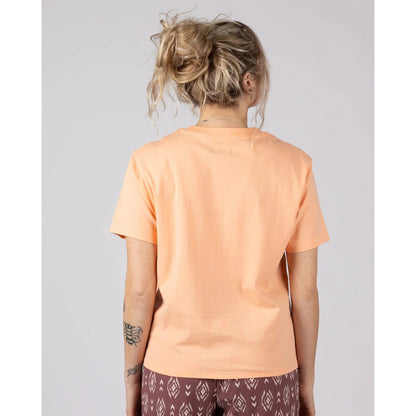 Back view of a woman wearing a Saltrock short sleeve Trader Daze t-shirt in peach, with a knot tie hem.