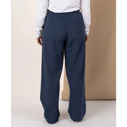 Woman wearing Saltrock Velator sweat trousers in blue marl and a white shirt against a beige background