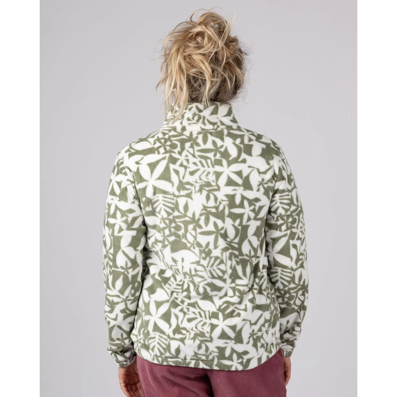 Back view of a woman wearing a Saltrock green floral patterned Balance fleece on a grey background