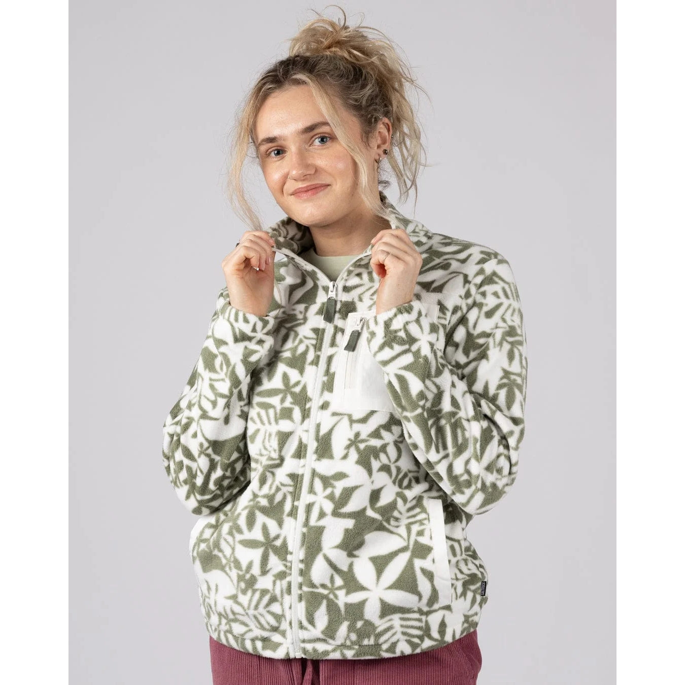 Front view of a woman wearing a Saltrock green floral pattern Balance fleece on a plain background