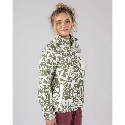 Side view of a woman wearing a green floral patterned Saltrock Balance fleece on a plain background